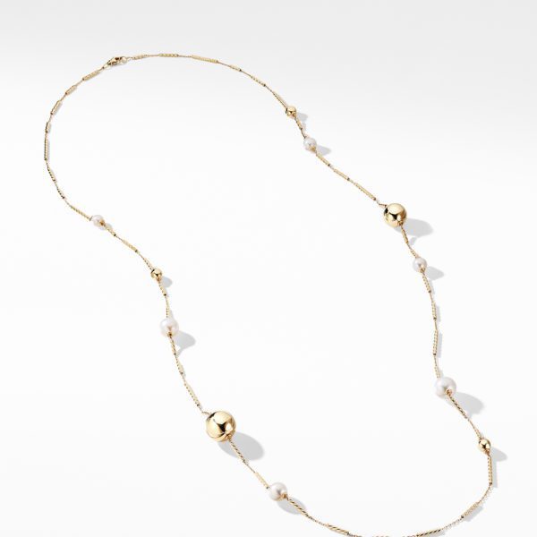 A delicate gold chain necklace is adorned with evenly spaced small pearls and larger round gold beads. The design is elegant and minimalistic, set against a plain white background.