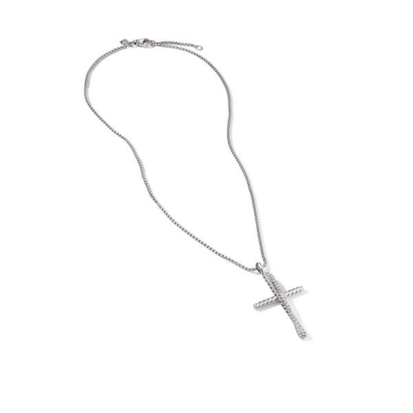 A silver necklace with a cross pendant lies on a white background. The cross has a textured design, while the chain is delicate with a simple clasp. The overall look is minimalistic and elegant.