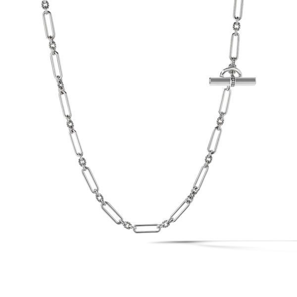 A close-up of a silver chain necklace with elongated oval links and a toggle clasp, set against a plain white background. The necklace's design is minimalistic and modern.