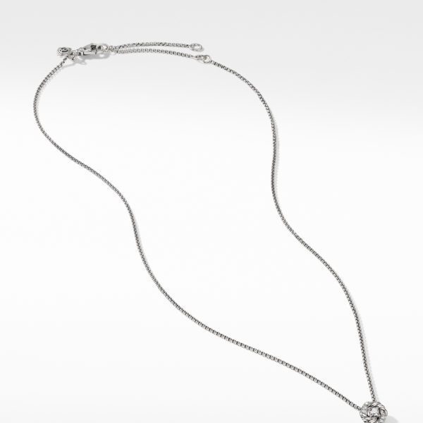 A delicate silver necklace with a thin chain and a small, intricate pendant is shown against a plain white background. The pendant appears to feature an ornate design, possibly floral or abstract. The clasp is a simple hook and loop style.