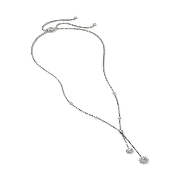 A delicate silver lariat necklace featuring a thin chain adorned with small, sparkling crystals. The chain extends downward, branching into two strands, each ending with a crystal-encrusted flower-shaped pendant. The necklace has an adjustable slider clasp.