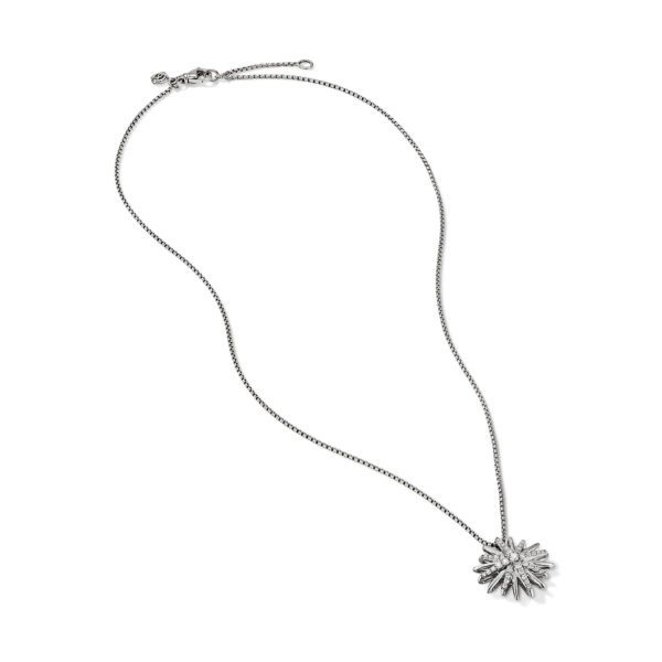 A delicate silver necklace featuring a chain with a sunburst or starburst pendant. The pendant is adorned with small, sparkling stones, giving it a radiant appearance. The necklace has a clasp for fastening. Set against a plain white background.