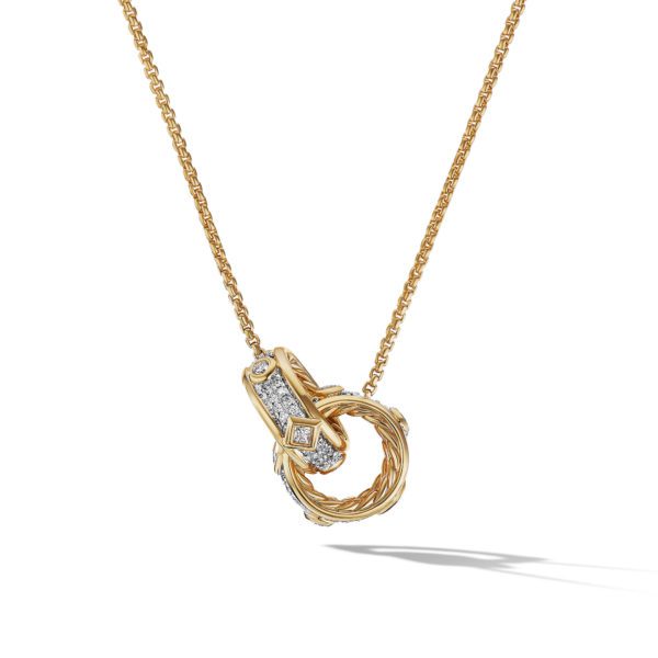 A gold necklace with a chain-link design features a pendant with two interlocking loops. One loop is plain gold while the other is adorned with small, sparkling diamonds. The necklace is photographed against a white background, casting a light shadow on the surface.