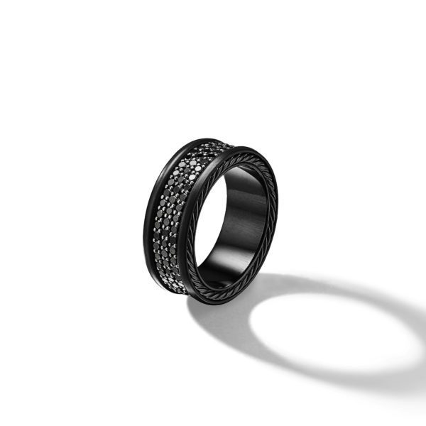 A black ring with a wide band features two rows of small, sparkly stones set within a braided pattern in the center. The ring casts a distinct shadow on the white background.