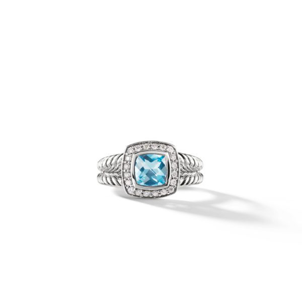 A silver ring featuring a rectangular-cut light blue gemstone set in the center, surrounded by small white stones. The band is designed with a twisted, rope-like texture. The ring is placed against a plain white background, casting a soft shadow.