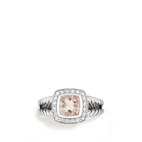 A silver ring with a textured band features a cushion-cut, light pink gemstone set in the center. The gemstone is surrounded by a halo of small, sparkling white stones, enhancing its elegance and brilliance.