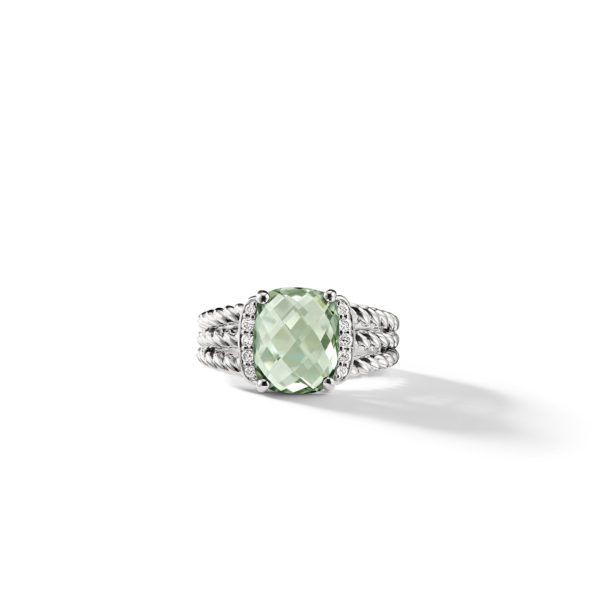 A silver ring featuring an oval-cut green gemstone in the center, surrounded by small round diamonds. The band has a twisted cable design and the ring is set against a white background.