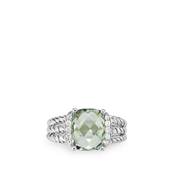 A silver ring with a large, faceted, light green gemstone at its center. The ring band consists of multiple twisted strands and the gemstone is flanked by small, round, clear stones on either side. The background is white.