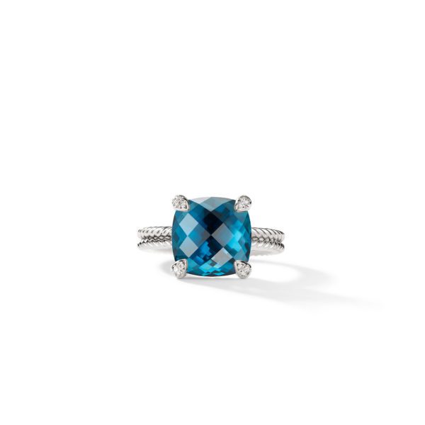 A silver ring featuring a large, square-cut blue gemstone set in the center with four prongs, displayed against a white background. The band is textured with a twisted design.