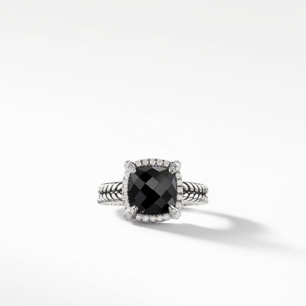 A square-cut black gemstone ring with a sparkling diamond halo set on a silver band, featuring a rope-like texture. The ring is positioned on a smooth, white background with a slight shadow.