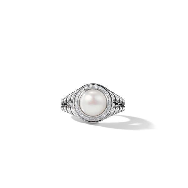 A silver ring featuring a large, round pearl in the center, surrounded by a halo of small diamonds. The band has a textured design, giving a sophisticated and elegant look. The ring casts a soft shadow on a white background.