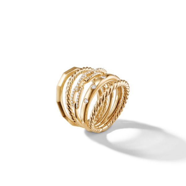 A stack of seven gold rings with various designs, displayed standing upright. Some rings feature twisted rope patterns, while others are adorned with small diamonds. The rings cast a soft shadow against the white background.