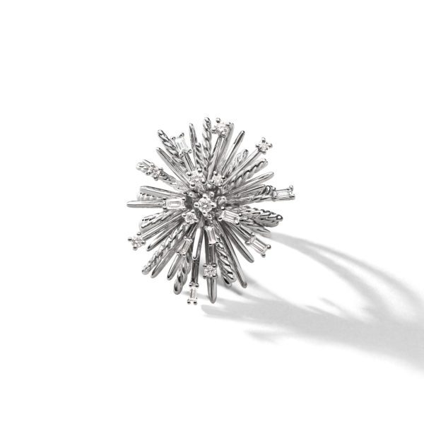 A silver starburst brooch with intricate metal spikes and circular accents radiating from the center, casting a soft shadow on a plain white background.