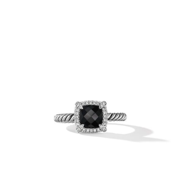 A silver ring with a twisted band design features a square-shaped, faceted black gemstone at its center. The gemstone is surrounded by a halo of small, sparkling clear stones. The ring is displayed on a white background.