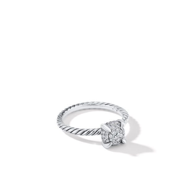 A silver ring with a twisted band and a cluster of small diamonds forming a sparkling cushion-shaped head is displayed on a white background. The ring casts a delicate shadow to the right.