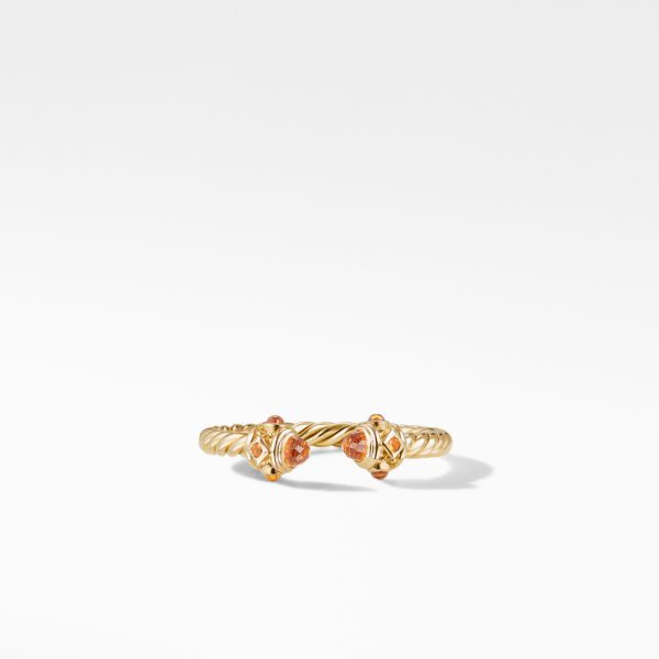 A gold twisted ring featuring two small, round orange gemstones set on either end. The minimalistic design showcases the elegant twist of the band, making the ring look intricate and delicate against the white background.