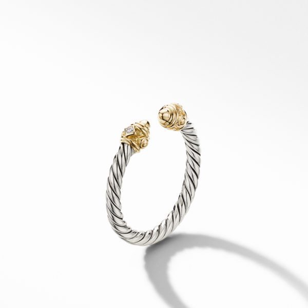 A silver twisted cable bracelet with gold accents and intricate detailing on both ends, designed in an open cuff style, casting a shadow on a white background.