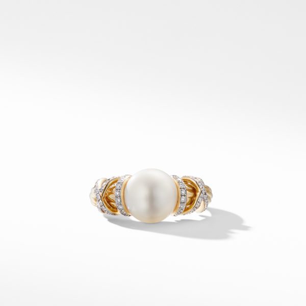 A gold ring featuring a large oval pearl at the center, flanked by intricate designs with small diamonds set in a wavy arrangement on either side. The ring is illuminated against a clean white background, casting a subtle shadow.