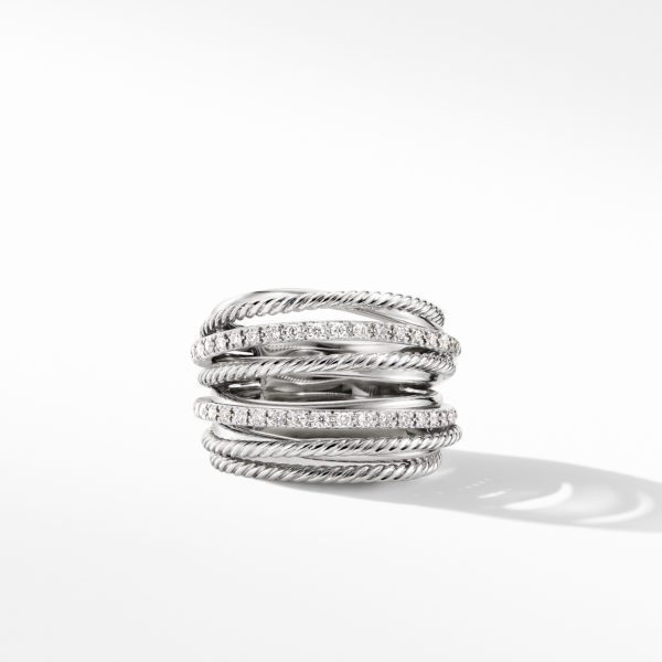 A silver ring featuring a multi-band design with alternating twisted and smooth textures. Several of the bands are adorned with small, sparkling diamonds, creating an elegant and intricate look. The ring is placed on a white surface with a soft shadow cast underneath.