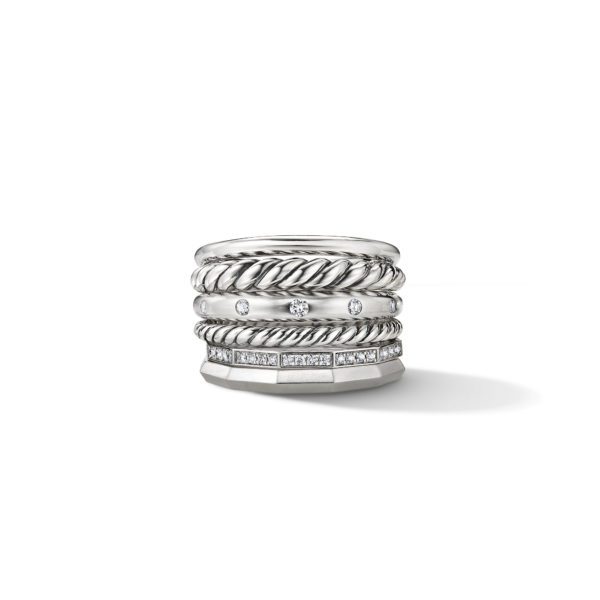 A stylish silver ring featuring multiple bands stacked together. The bands display various designs, including twisted textures and embedded small diamonds, offering a mix of elegance and contemporary flair. The ring casts a subtle shadow to its right.