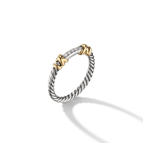 A delicate ring featuring a twisted silver band adorned with golden accents and small diamonds embedded in a bar at the top. The ring casts a subtle shadow on a white background.