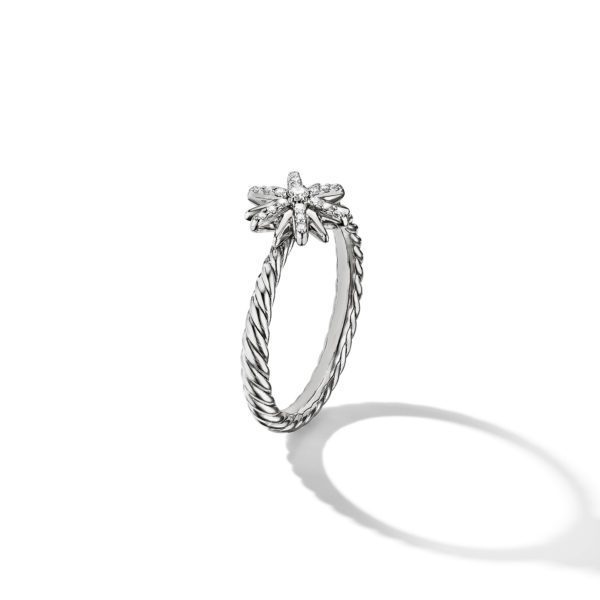 A silver ring with a twisted band design is set with a delicate star-shaped cluster of small diamonds at the top. The ring casts a subtle shadow on a plain white background.