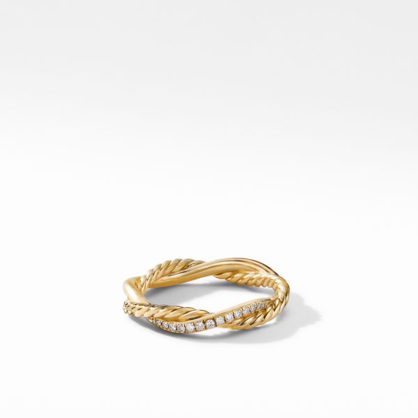 A gold twisted rope ring with a section encrusted with small diamonds rests on a white surface. The ring features a combination of smooth gold and textured rope design, creating a elegant and sophisticated appearance.