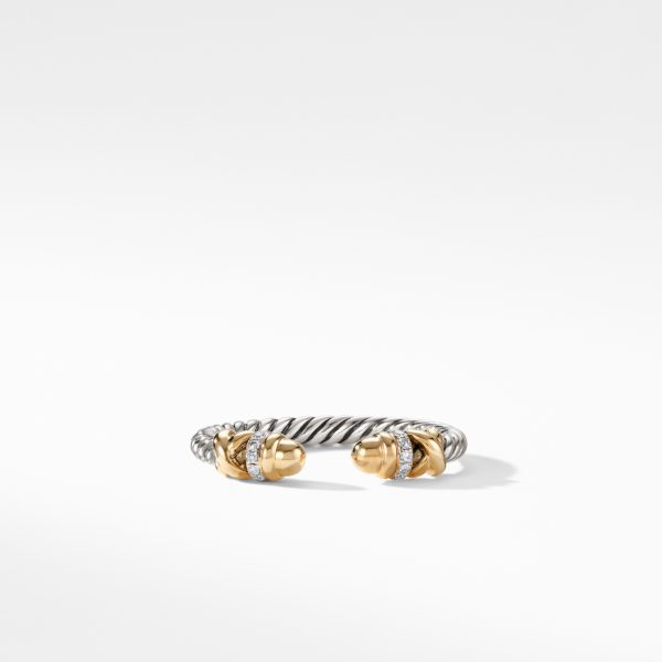 A silver-toned twisted cable bracelet with gold-toned capped ends adorned with small gemstones. The bracelet is laid on a white surface, highlighting its elegant and minimalist design.