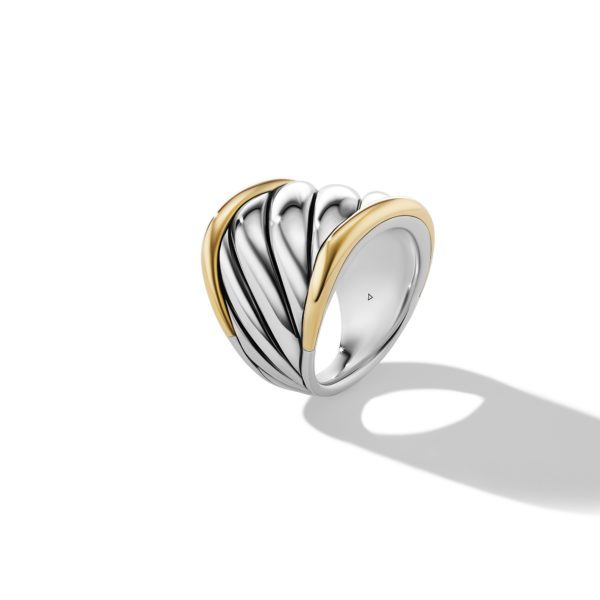 A silver ring with a wide band and a unique design pattern resembling waves. The top portions feature gold accents that outline the curves of the wave-like design. The ring casts a shadow on the white background.