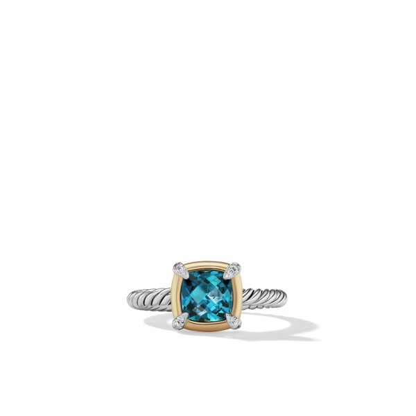 A ring with a twisted silver band featuring a square-cut blue gemstone set in a gold bezel with four-prong settings. The gemstone sparkles, and the prongs are embellished with small, clear diamonds. The ring is displayed against a plain white background.