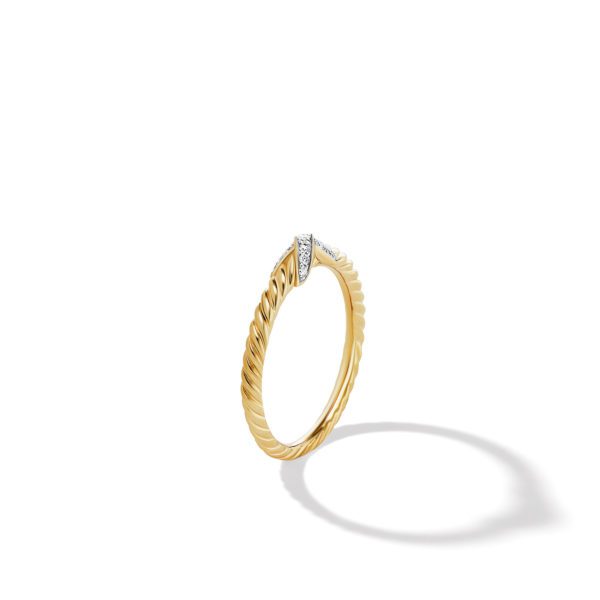 A slim, gold ring with a textured band and a small cluster of diamonds at the top, creating a subtle, elegant sparkle. The ring casts a delicate shadow on a white background, emphasizing its simple yet sophisticated design.