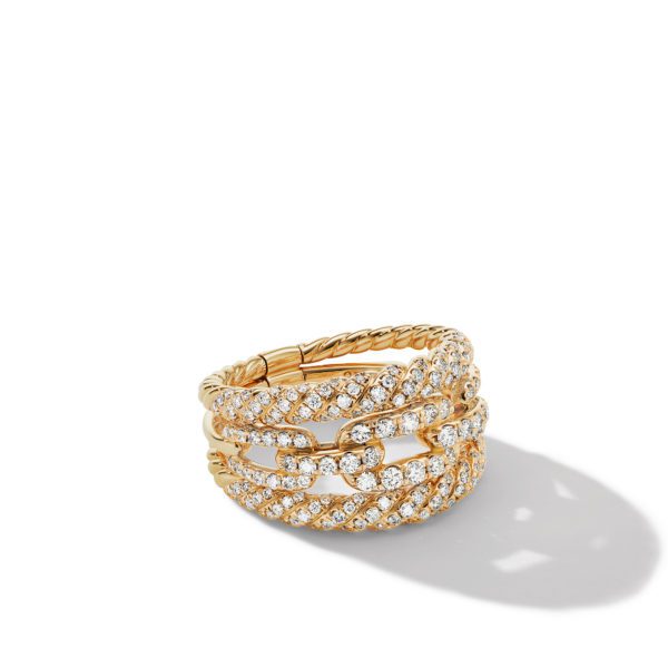 A gold ring featuring multiple intertwined bands adorned with sparkling diamonds, casting a faint shadow on a white surface.