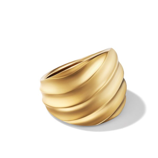 A gold ring with a wide band that has a twisted, sculptural design. The ring's surface features smooth, flowing ridges, creating a dynamic and elegant appearance. It casts a soft shadow on the white background.