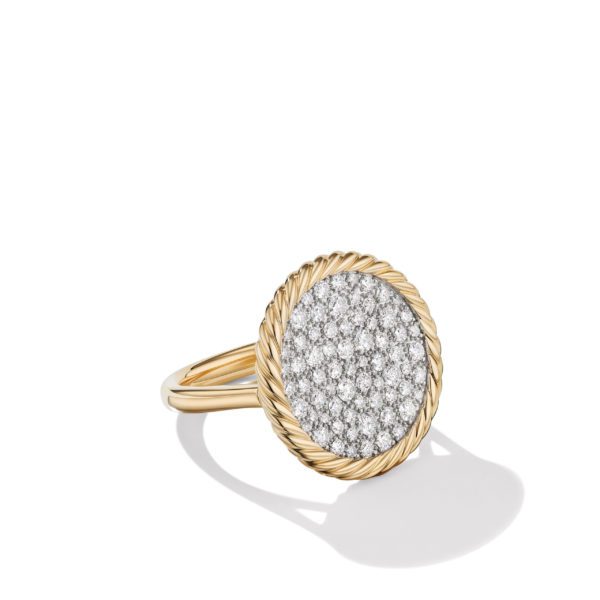 A gold ring featuring a round face encrusted with numerous small diamonds. The round face is bordered by a twisted rope design in gold, with the rest of the band being smooth gold. The ring casts a shadow on the white background.