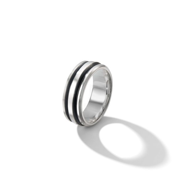 A sleek silver ring with two parallel black grooves encircling its exterior, casting a distinct shadow on a white surface. The simple yet modern design contrasts the metallic shine of the silver with the matte finish of the black grooves.