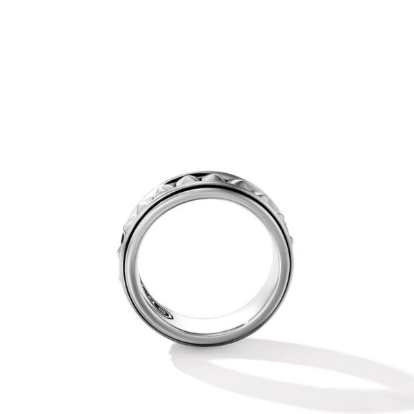 A sleek, silver band ring with a subtle geometric pattern on the outer surface, photographed on a white background. The ring is positioned upright, casting a soft shadow to the right.