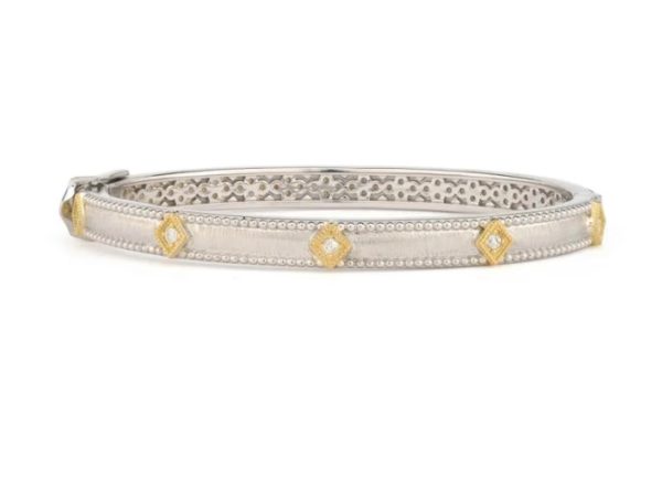 The JudeFrances Mixed Metal Lisse Diamond Kite Bangle is a sleek silver bracelet featuring yellow diamond-shaped accents and intricate, detailed engravings on the outer side with an ornate pattern on the inner side, embodying a refined and elegant design.