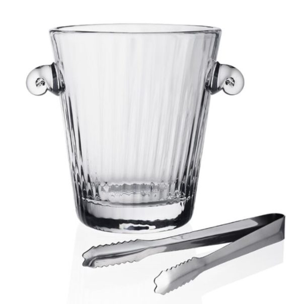 The William Yeoward Corinne Ice Bucket with Tongs is displayed, featuring a clear glass bucket with ribbed sides and two rounded handles. Beside the bucket, there is a pair of stainless steel ice tongs with serrated edges. The setting showcases both items on a plain white background.