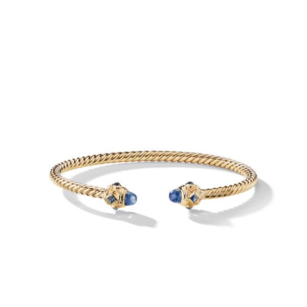 A gold twisted rope cuff bracelet with blue and gold gemstone caps at each end. The bracelet is open-ended and displayed against a plain white background. The gemstones add a touch of elegance and contrast to the gold rope detail.