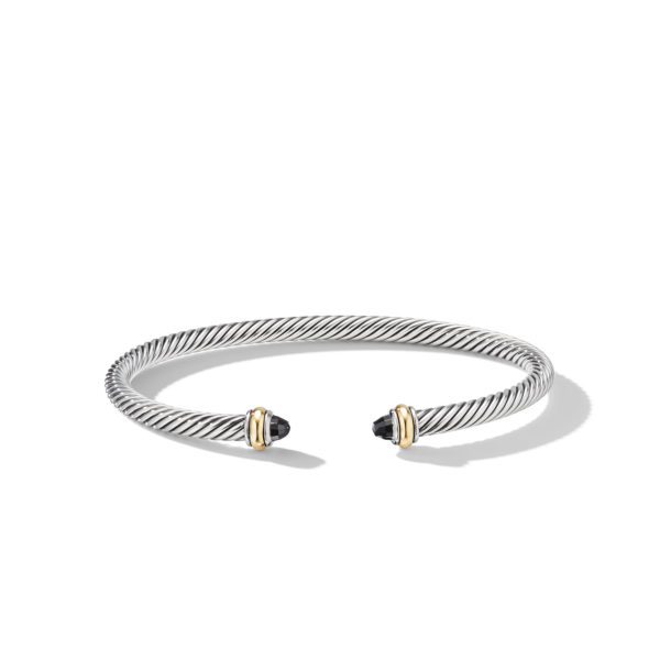 A sleek, twisted silver bracelet with gold accents at the open ends, each end featuring a small, round black gemstone. The bracelet casts a faint shadow on the white background.