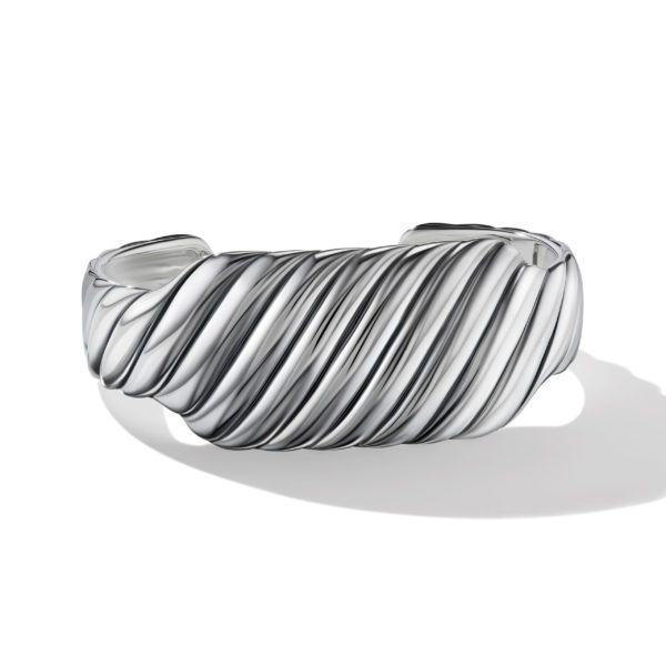 A silver cuff bracelet featuring a twisted, rope-like design. The shiny metallic surface reflects light, showcasing its intricate texture and polished finish. The bracelet is against a white background, creating a shadow that adds depth to the image.