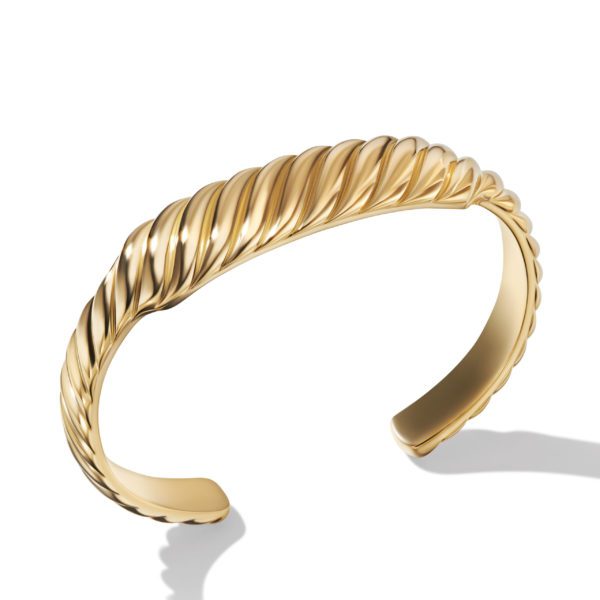 A close-up view of a gold cuff bracelet with a twisted rope design. The bracelet is open at the back and casts a soft shadow on a white background. The polished metal surface reflects light, accentuating its shiny and elegant appearance.