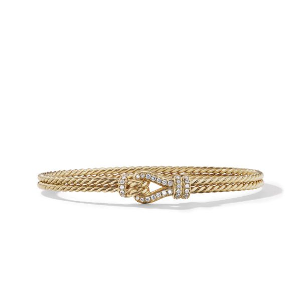 A gold bracelet with twisted rope design featuring a decorative clasp adorned with small, shiny diamonds. The clasp resembles an elegant knot, adding a touch of sophistication to the jewelry piece. The bracelet has a polished and refined finish.