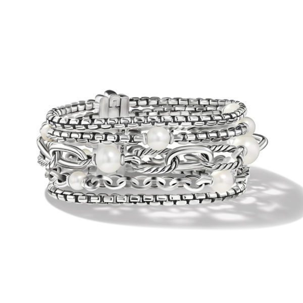 A silver bracelet composed of multiple layered chains adorned with white pearls is coiled in a spiral formation on a white background. The bracelet has intricate, interwoven designs, combining smooth and textured elements, with a clasp closure.