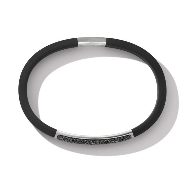 A sleek black bracelet with a silver clasp and an accent section adorned with small, black stones. The bracelet is simple and elegant, with a modern design. The lighting creates a subtle shadow beneath the bracelet, accentuating its shape.