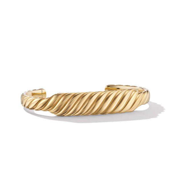 A gold bracelet with a twisted, rope-like design is displayed against a white background. The bracelet has an open, cuff-style structure with a polished finish, casting a shadow on the surface below.