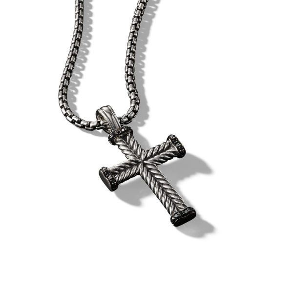 A metallic cross pendant with a rope-like texture hangs from a sleek and sturdy chain. The cross has a dark finish with darker accents at the ends, and is photographed against a plain white background, casting soft shadows.