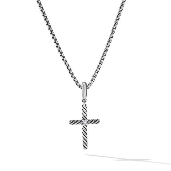 A silver cross pendant with a textured design hangs from a matching silver chain. The cross has a delicate, horizontal-etched pattern and is suspended from a small loop. The chain has a slight shadow cast on a white background.