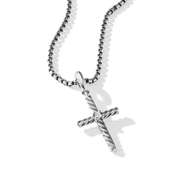 A silver twisted rope-design cross pendant hangs from a black and white mixed chain against a white background. The pendant has a clear gemstone at the intersection of the cross. The chain features a box-link pattern with a combination of black and silver links.