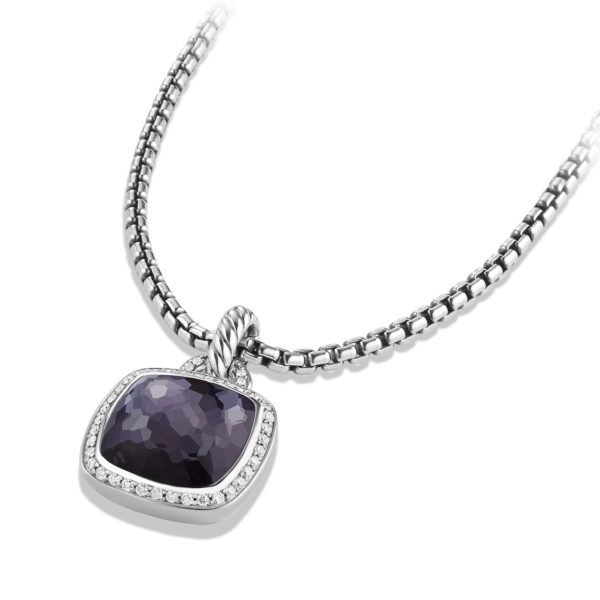 A close-up image of a silver necklace featuring a rectangular faceted purple pendant, bordered with small clear stones. The pendant hangs from a textured bail on a thick, elegant silver chain. The necklace has an overall luxurious and sophisticated appearance.